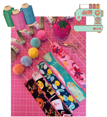 Sewing machine, thread spools, pom-poms, and fabric.