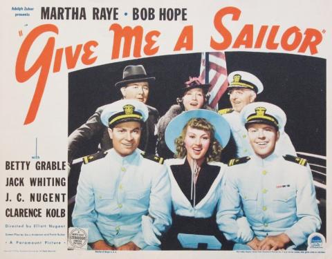 Give Me A Sailor placard of 6 men and women sitting 