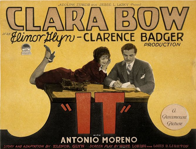 Woman laying on her stomach and man standing over the word It