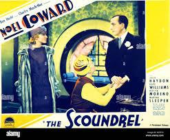 Woman in 1920's dress, plus a man in a suit standing, with another man sitting.